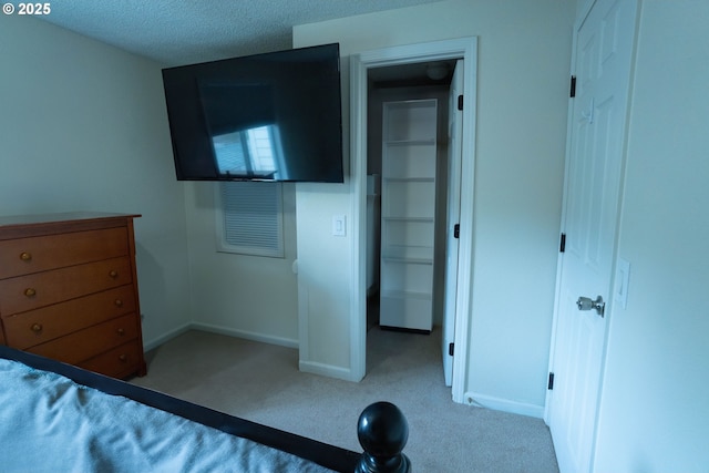 unfurnished bedroom with light colored carpet, a spacious closet, and a textured ceiling