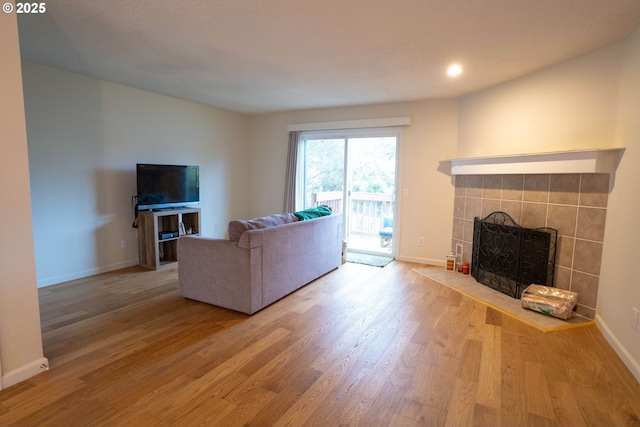 unfurnished living room with a tiled fireplace and hardwood / wood-style floors