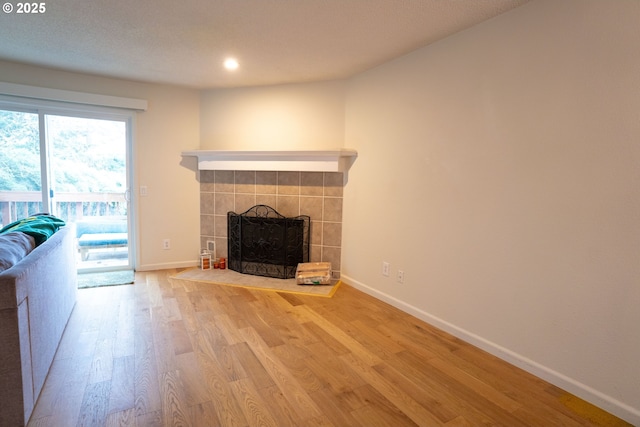 unfurnished living room featuring a tile fireplace and hardwood / wood-style floors