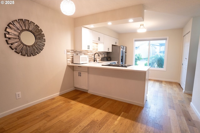 kitchen with decorative backsplash, stainless steel fridge with ice dispenser, white cabinets, and kitchen peninsula