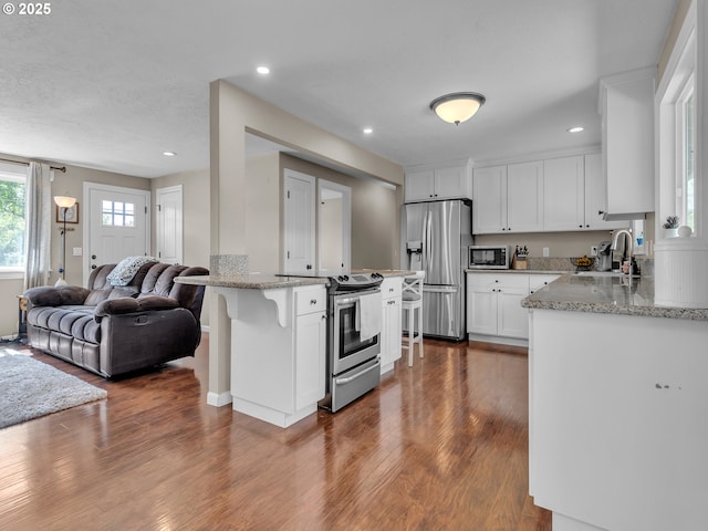 426 NE Hill St, Sheridan, OR 97378 - kitchen with stainless steel appliances, a sink, open floor plan, wood finished floors, and white cabinetry