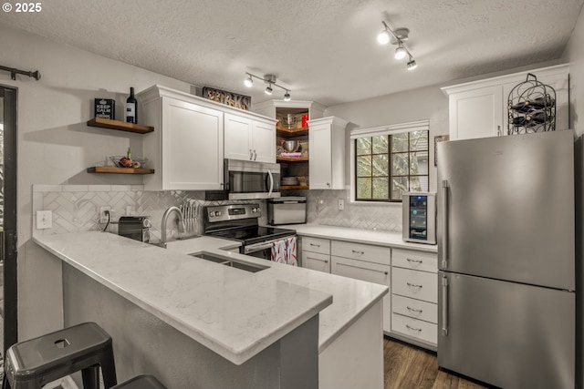 kitchen with kitchen peninsula, a breakfast bar, white cabinets, and stainless steel appliances