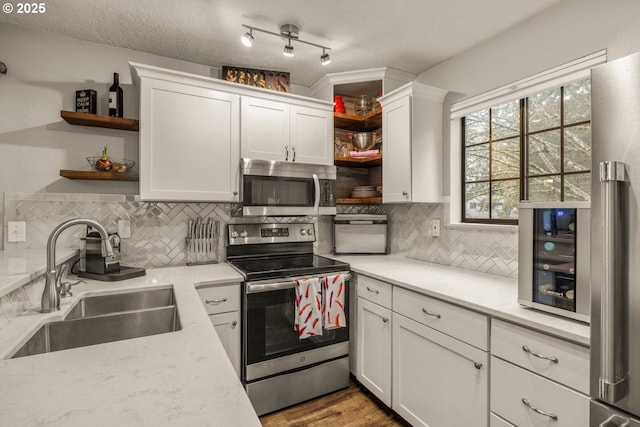 kitchen featuring sink, backsplash, a textured ceiling, white cabinets, and appliances with stainless steel finishes