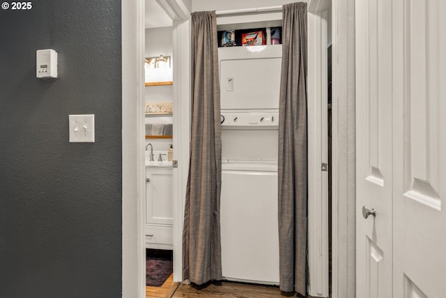 laundry area featuring stacked washer and dryer, hardwood / wood-style floors, and sink