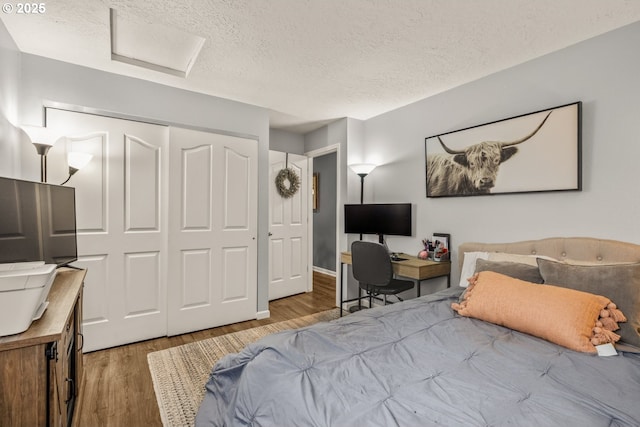 bedroom with a textured ceiling, hardwood / wood-style flooring, and a closet