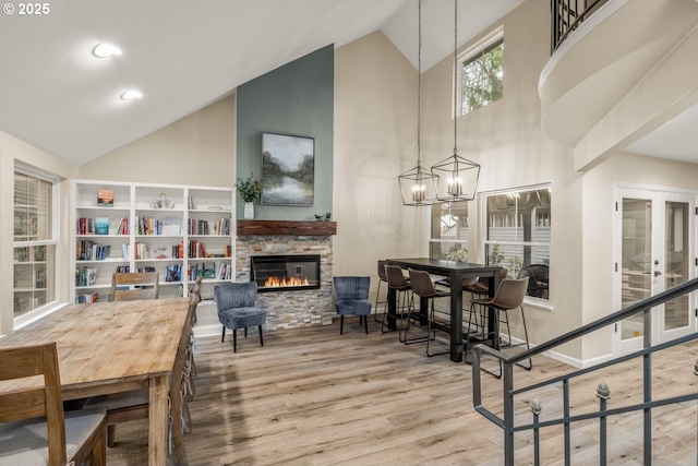 interior space with a notable chandelier, wood-type flooring, a fireplace, and high vaulted ceiling