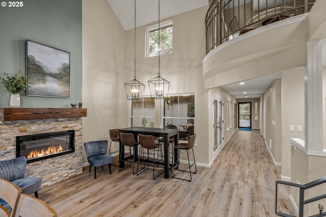 interior space featuring a wealth of natural light, a fireplace, high vaulted ceiling, and light hardwood / wood-style flooring