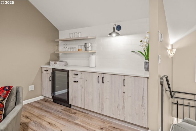 kitchen featuring light hardwood / wood-style floors, lofted ceiling, light brown cabinets, and wine cooler