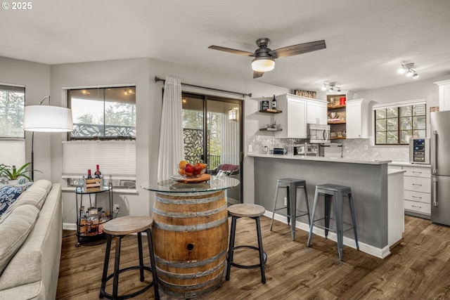 kitchen with white cabinetry, a kitchen breakfast bar, kitchen peninsula, decorative backsplash, and appliances with stainless steel finishes