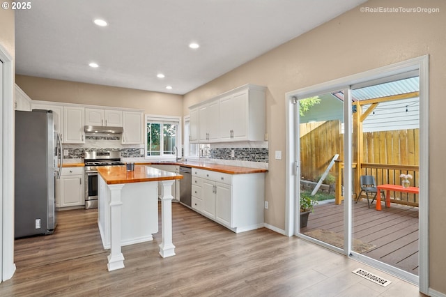 kitchen with sink, butcher block countertops, white cabinetry, a kitchen island, and stainless steel appliances