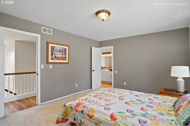 carpeted bedroom with a textured ceiling and ensuite bathroom