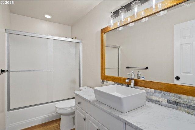 full bathroom featuring enclosed tub / shower combo, vanity, toilet, and wood-type flooring