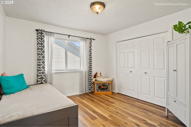 bedroom featuring hardwood / wood-style floors, a textured ceiling, and a closet