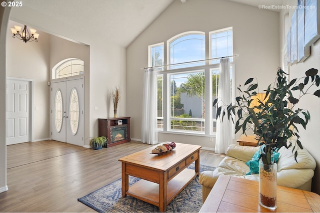 living room featuring hardwood / wood-style floors, a notable chandelier, and high vaulted ceiling