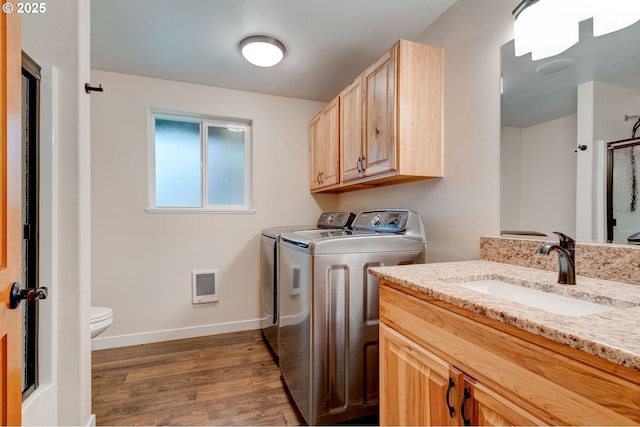 washroom featuring dark wood finished floors, heating unit, a sink, independent washer and dryer, and baseboards