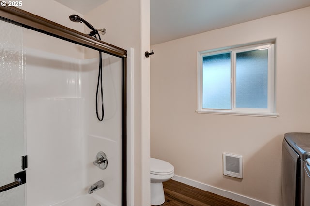 bathroom with toilet, wood finished floors, baseboards, heating unit, and washing machine and clothes dryer