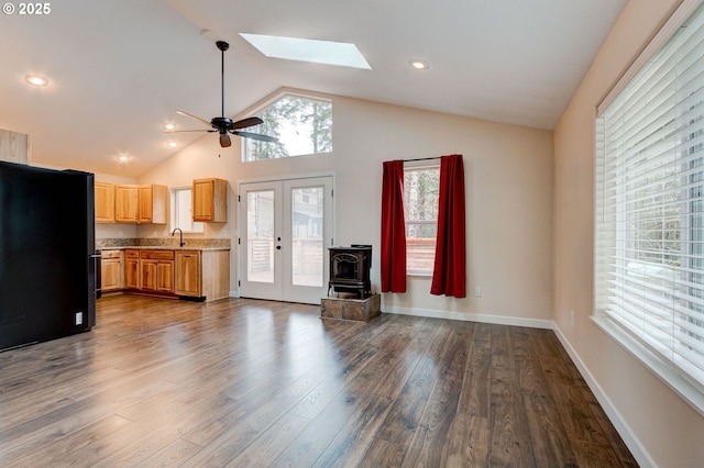 unfurnished living room with dark wood-type flooring, a skylight, a sink, baseboards, and french doors