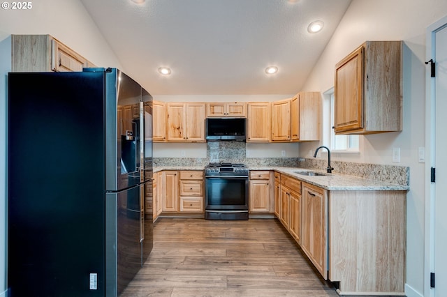 kitchen featuring stainless steel fridge, light brown cabinetry, a sink, and range with gas cooktop