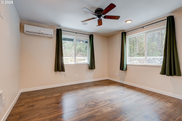 unfurnished room featuring baseboards, a wall mounted air conditioner, wood finished floors, and a healthy amount of sunlight