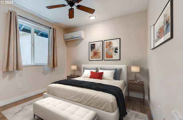 bedroom featuring an AC wall unit, ceiling fan, baseboards, and wood finished floors