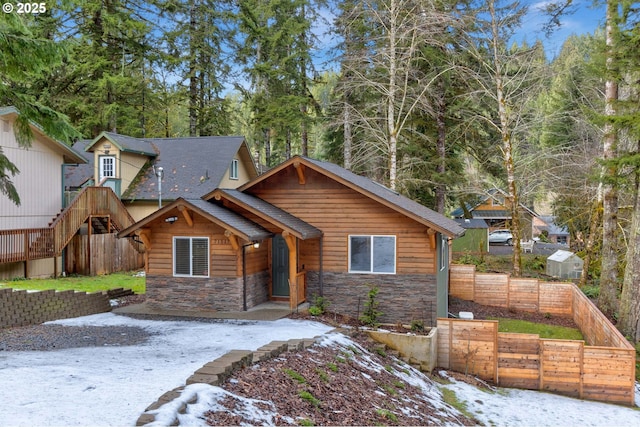 view of front of home with stone siding and fence