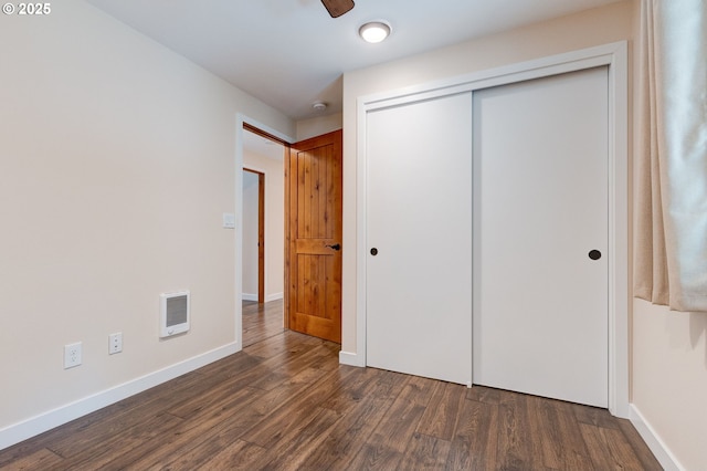 unfurnished bedroom with a closet, visible vents, dark wood finished floors, and baseboards