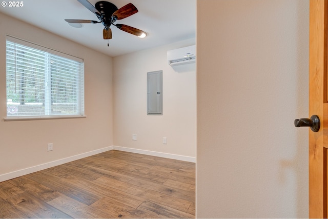 unfurnished room with electric panel, baseboards, a ceiling fan, wood finished floors, and a wall mounted air conditioner