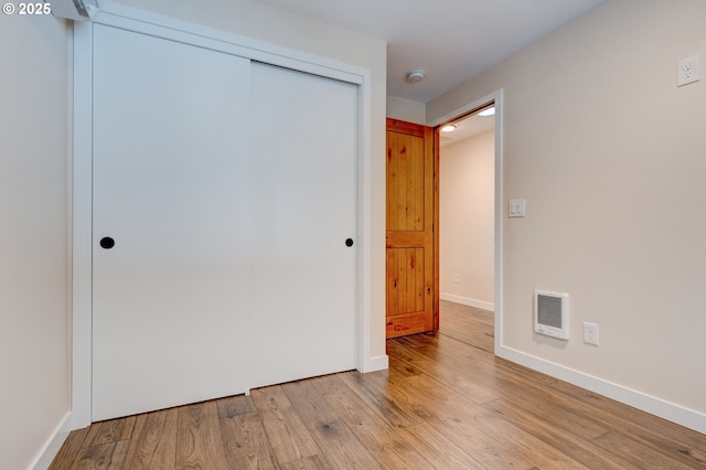 unfurnished bedroom featuring light wood finished floors, baseboards, visible vents, and a closet