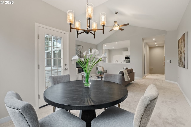dining area featuring baseboards, vaulted ceiling, light carpet, and ceiling fan with notable chandelier