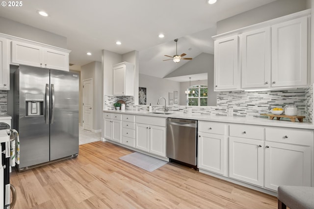 kitchen with appliances with stainless steel finishes, tasteful backsplash, a sink, white cabinets, and light wood-style flooring