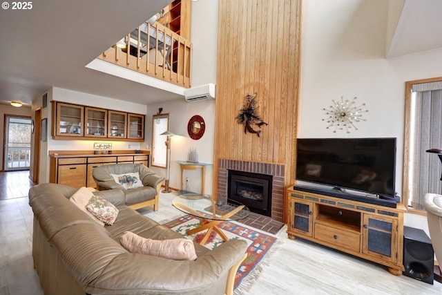 living room featuring a brick fireplace, a high ceiling, and a wall mounted AC