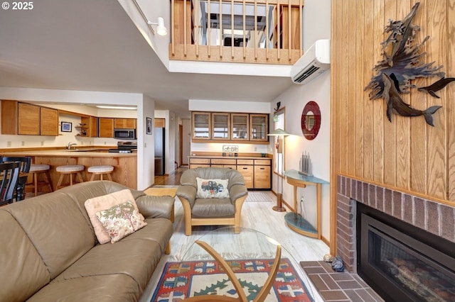 821 5th Ave, Hammond, OR 97121 - living room featuring a wall mounted AC, light wood-style flooring, and a brick fireplace