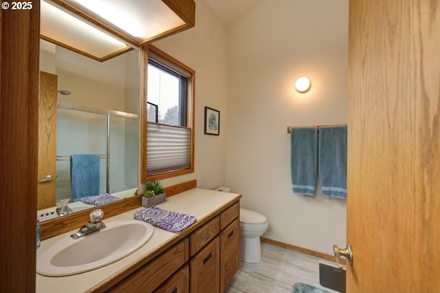 bathroom featuring toilet, a stall shower, vanity, and baseboards