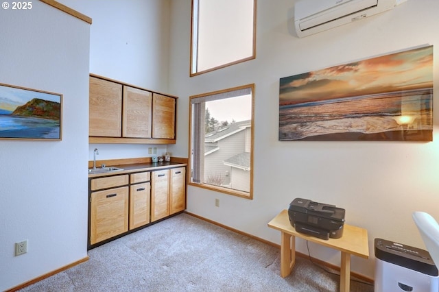 interior space with a wall mounted air conditioner, a sink, light colored carpet, and baseboards