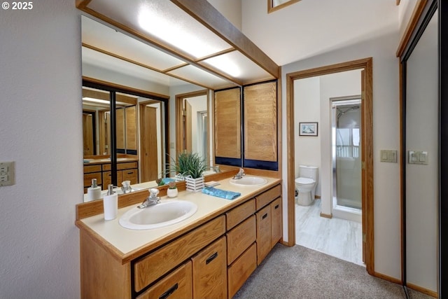 full bathroom featuring toilet, double vanity, baseboards, and a sink