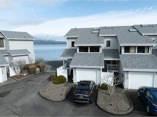 view of front of property featuring a water view, a shingled roof, aphalt driveway, and an attached garage