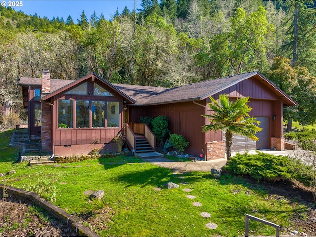 rustic home featuring a front lawn, a view of trees, crawl space, brick siding, and a chimney