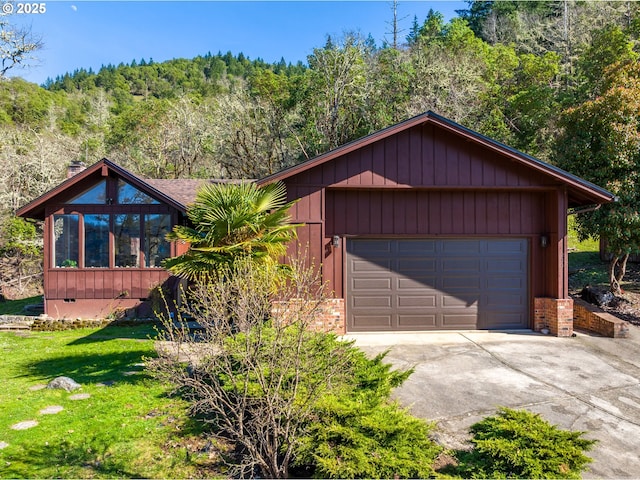 chalet / cabin with brick siding, a wooded view, a front lawn, crawl space, and driveway