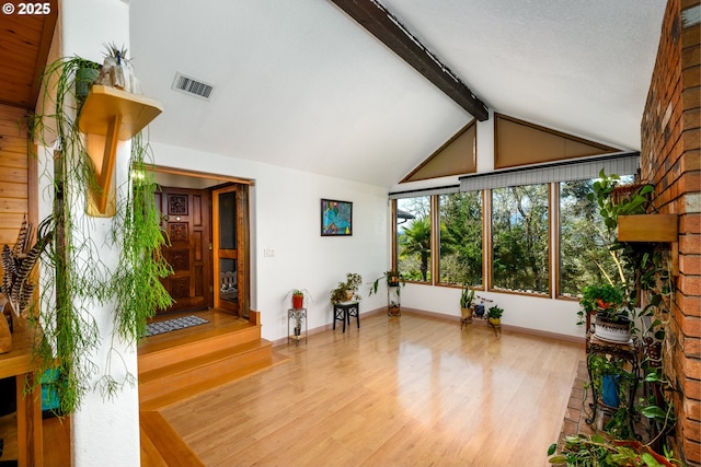 living room featuring visible vents, baseboards, beam ceiling, wood finished floors, and high vaulted ceiling