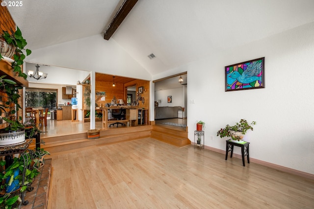 interior space with an inviting chandelier, beamed ceiling, wood finished floors, and visible vents