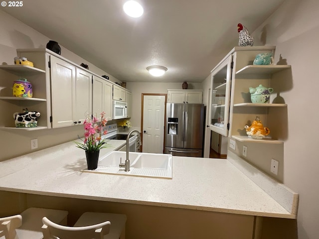 kitchen with white appliances, a peninsula, white cabinetry, and open shelves