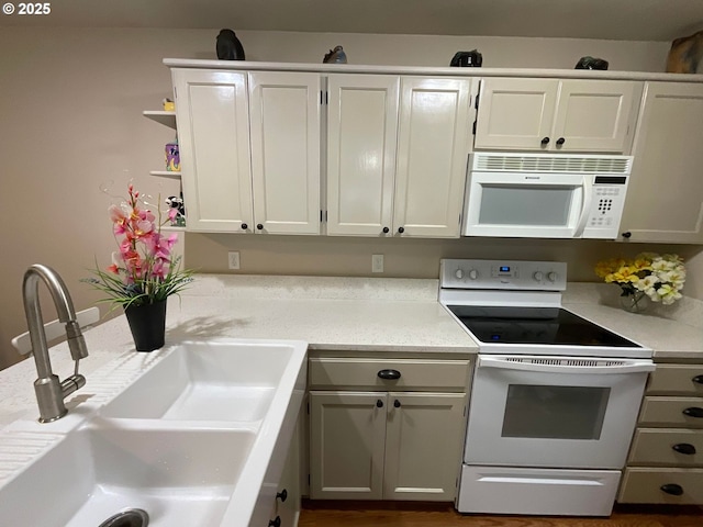 kitchen featuring white appliances, light countertops, a sink, and white cabinetry