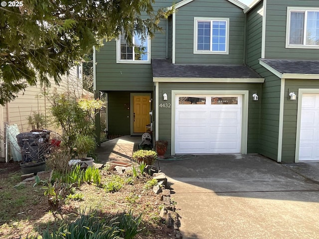 view of front facade with an attached garage, roof with shingles, and concrete driveway