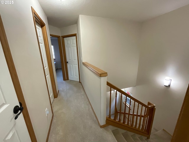 corridor featuring light carpet and an upstairs landing