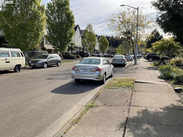 view of road featuring street lighting, sidewalks, a residential view, and curbs