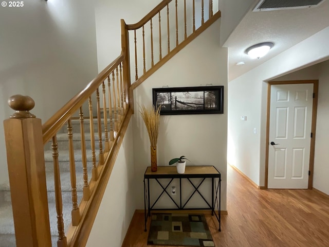 stairs featuring visible vents, baseboards, and wood finished floors