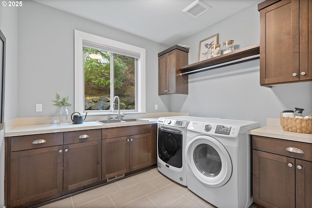 washroom with a sink, visible vents, cabinet space, and independent washer and dryer