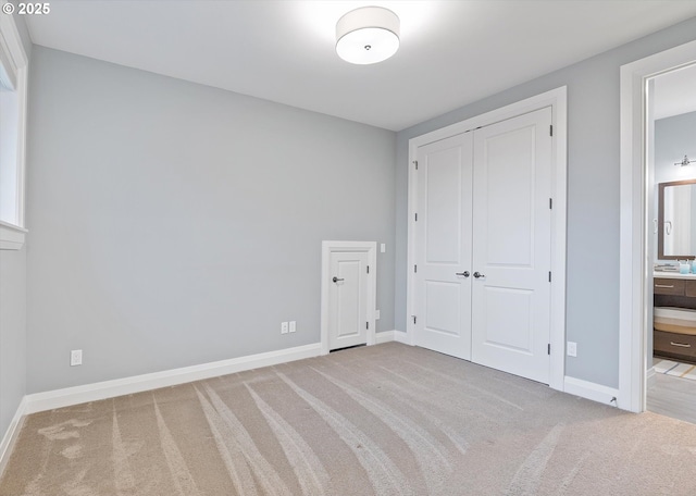 unfurnished bedroom with baseboards, carpet floors, a closet, and connected bathroom