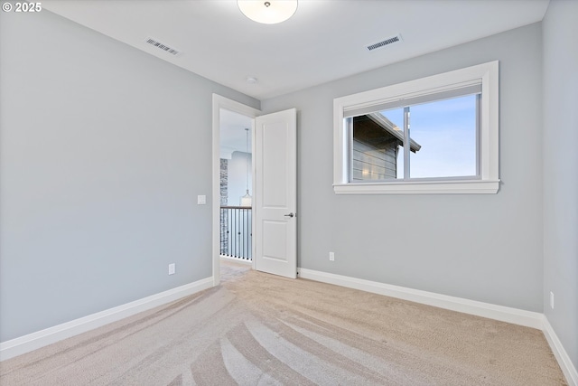 carpeted spare room with visible vents and baseboards