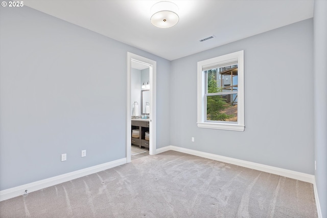 unfurnished bedroom with carpet flooring, visible vents, ensuite bath, and baseboards